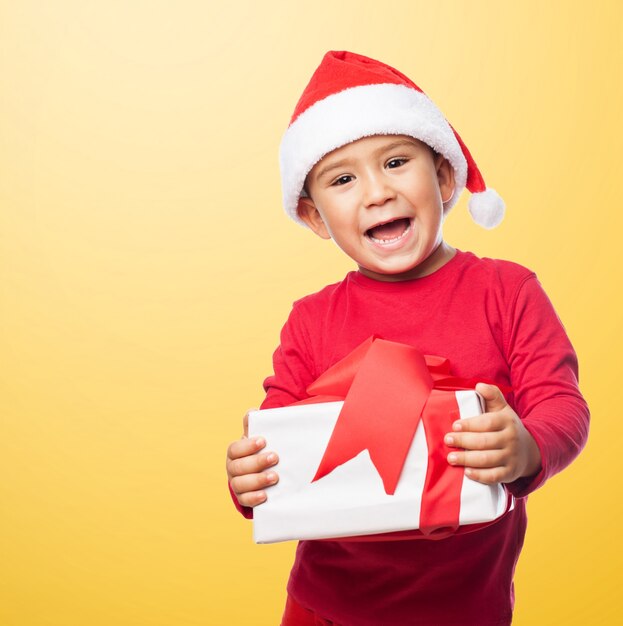 Kleiner Junge Weihnachten mit einem Geschenk zu feiern
