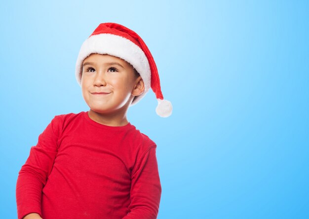 Kleiner Junge Weihnachten mit einem Sankt-Hut feiert