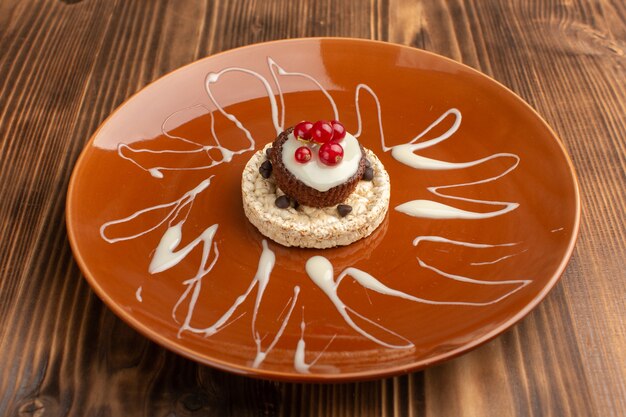 kleiner köstlicher Kuchen mit frischen Preiselbeeren des Crackers innerhalb der braunen Platte auf Holz