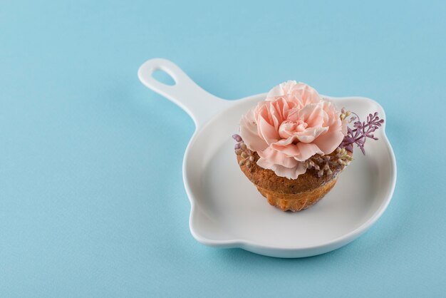 Kleiner Kuchen des hohen Winkels mit Blume und blauem Hintergrund