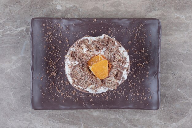 Kleiner Kuchen mit gehackter Orangenspitze auf einer Platte auf Marmor