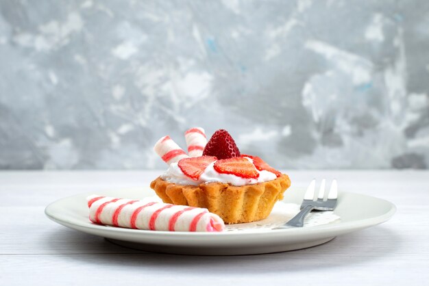 kleiner Kuchen mit Sahne und geschnittenen Erdbeeren in Teller auf weißem, süßem Obstkuchen-Beerenzucker