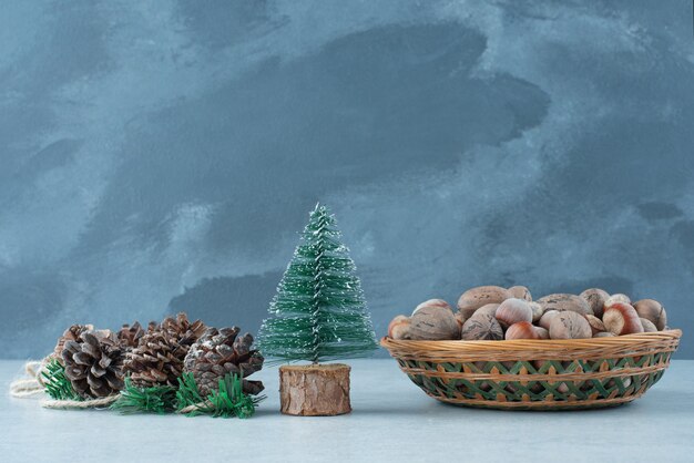 Kleiner Weihnachtsbaum mit Korb der Nüsse auf Marmorhintergrund. Hochwertiges Foto