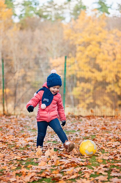 kleines Baby, das im Herbstlaub spielt