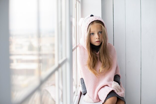 Kleines blondes Mädchen, das rosa Pullover trägt