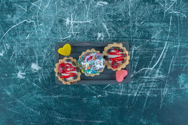 Kleines Bündel von Cupcakes und Marmelade auf einer Platte auf blauem Hintergrund. Hochwertiges Foto