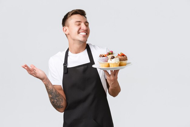 Kleines Einzelhandelsgeschäft, Cafés und Bäckereikonzept, das einen glücklichen, gutaussehenden Barista-Kellner im Laden lächelt...