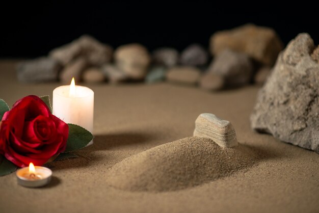 Kleines Grab mit Kerze und Steinen auf Sandbestattungskriegsmond