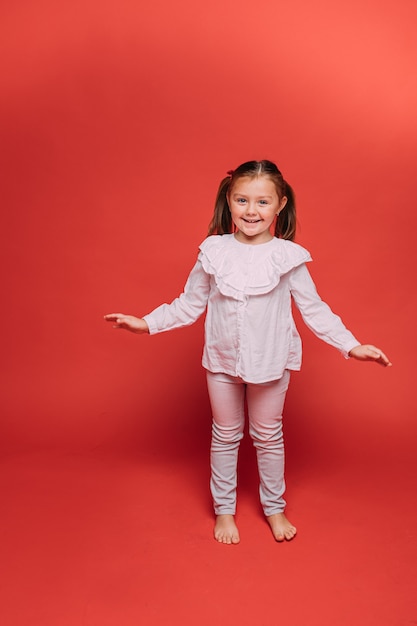 Kleines hübsches Mädchen hat viel Spaß im Fotostudio, Bild einzeln auf rotem Hintergrund