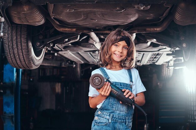 Kleines hübsches Mädchen posiert für Fotografen mit Werkzeug in der Autowerkstatt.