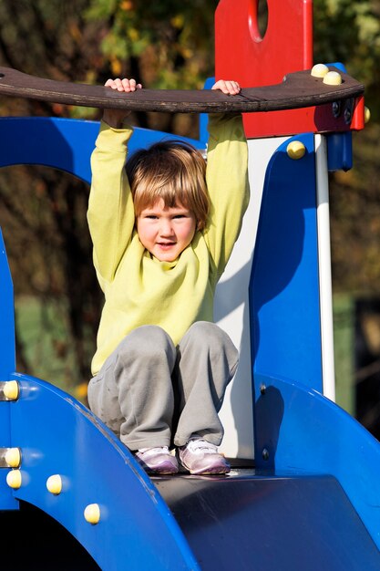 Kleines Kind, das auf buntem Spielplatz spielt