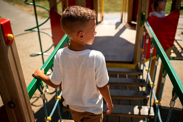 Kleines Kind, das sich auf dem Spielplatz im Freien amüsiert