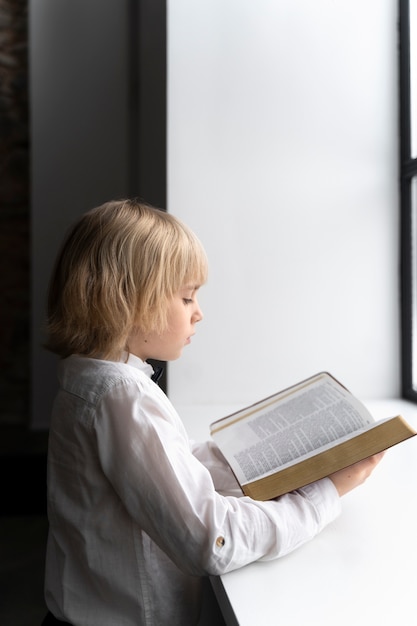 Kostenloses Foto kleines kind mit mittlerer aufnahme, das die bibel liest