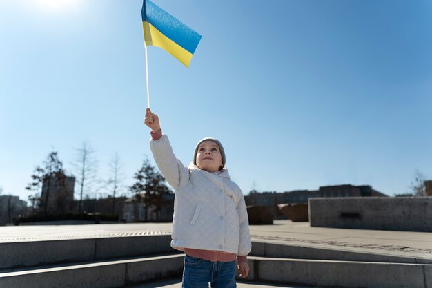 Kleines kind mit mittlerer aufnahme, das ukrainische flagge hält