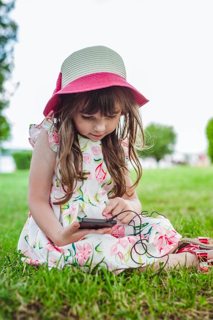 Kostenloses Foto kleines mädchen auf dem boden mit einem telefon in der hand sitzen