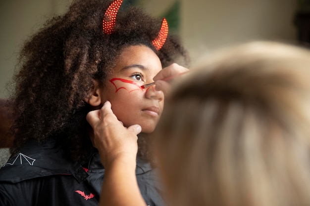 Kostenloses Foto kleines mädchen bereitet sich auf halloween mit einem teufelskostüm vor