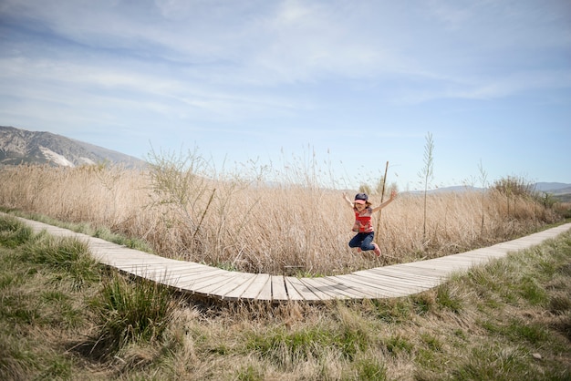 Kleines Mädchen, das auf einen Weg von hölzernen Brettern in einem Sumpfgebiet in Padul, Granada, Andalusien, Spanien geht