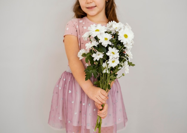Kleines Mädchen, das Blumenstrauß der Frühlingsblumen hält