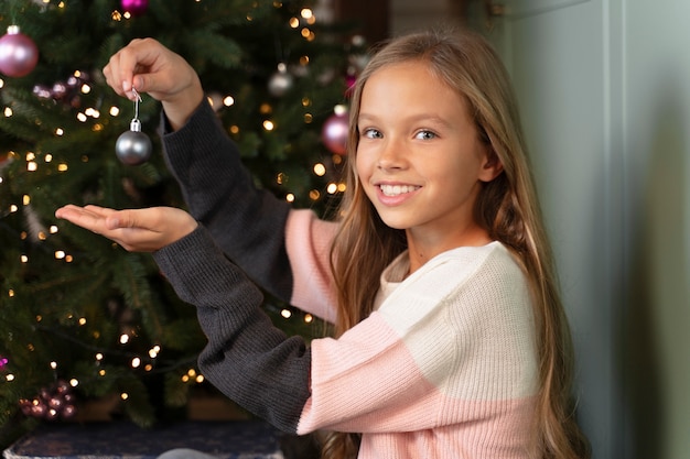 Kleines Mädchen, das den Weihnachtsbaum schmückt