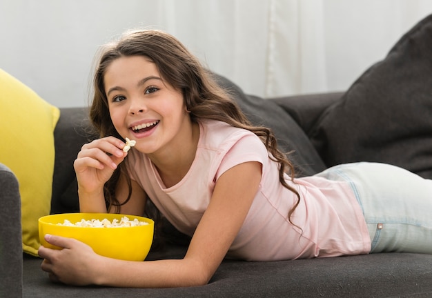 Kleines Mädchen, das eine Schüssel Popcorn genießt