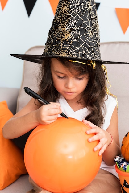 Kostenloses Foto kleines mädchen, das einen halloween-ballon zeichnet