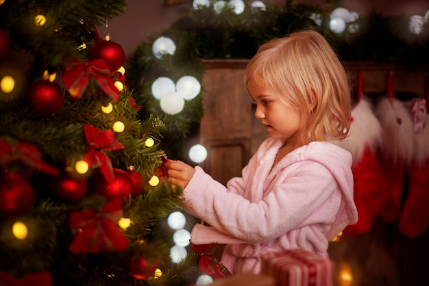 Kleines Mädchen, das einen Weihnachtsbaum verziert