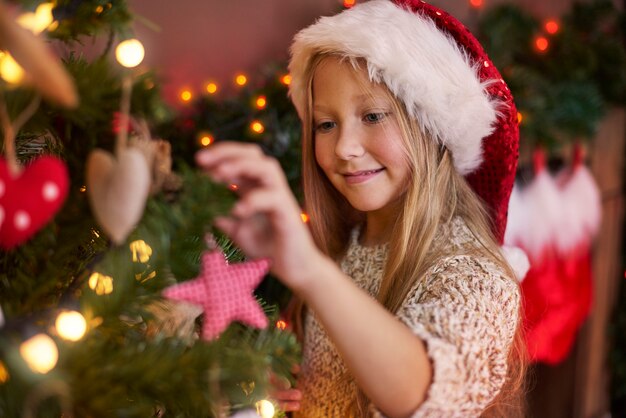 Kleines Mädchen, das einige Weihnachtsschmuck hängt