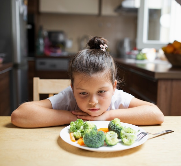 Kostenloses Foto kleines mädchen, das gesundes lebensmittel ablehnt