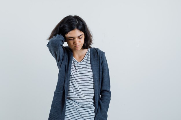 Kostenloses Foto kleines mädchen, das hand am hals im t-shirt, in der jacke hält und nachdenklich schaut,