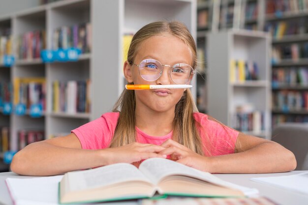 Kleines Mädchen, das in der Bibliothek dumm ist