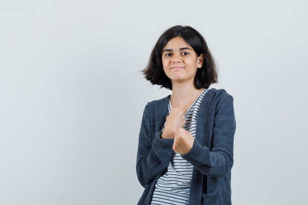 Kleines Mädchen, das in der Boxerhaltung im T-Shirt, in der Jacke steht und zuversichtlich schaut