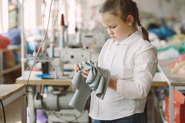 Kleines Mädchen, das in der Fabrik mit einem Faden steht