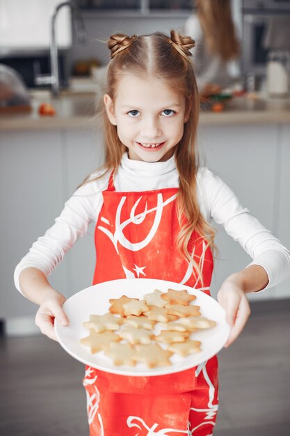 Kleines Mädchen, das in einer Küche mit Plätzchen steht