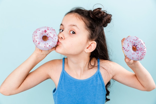 Kleines Mädchen, das köstlichen Donut küsst