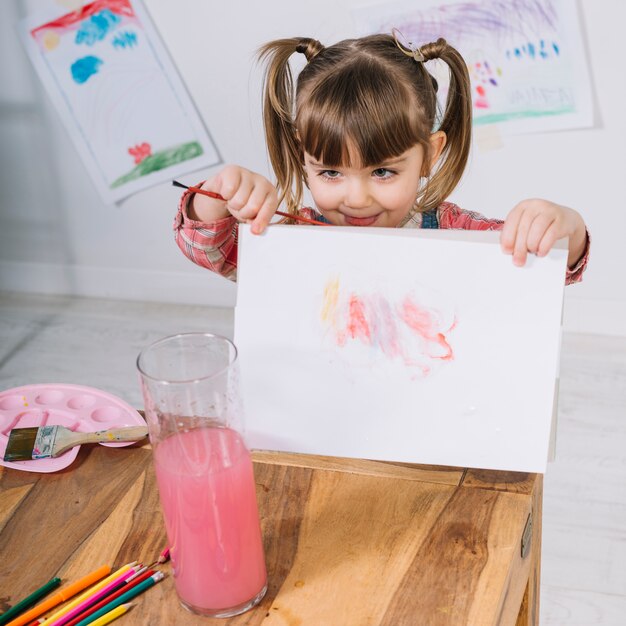 Kleines Mädchen, das Malerei auf Papier zeigt