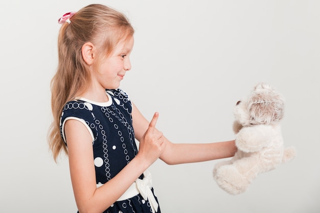 Kleines Mädchen, das mit ihrem Teddybären spricht