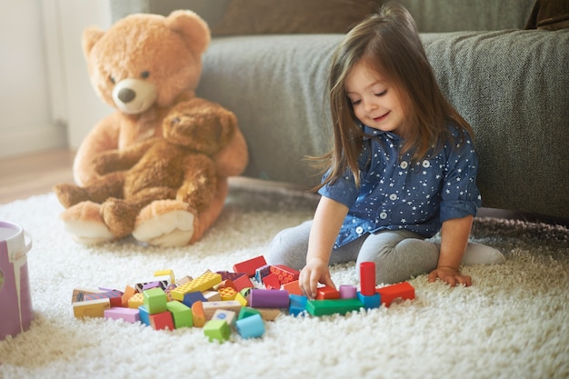 Kleines Mädchen, das mit Spielzeug am Wohnzimmer spielt