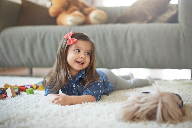 Kleines Mädchen, das mit Spielzeug am Wohnzimmer spielt