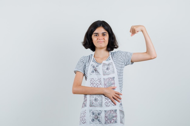 Kleines Mädchen, das Muskeln des Armes im T-Shirt zeigt