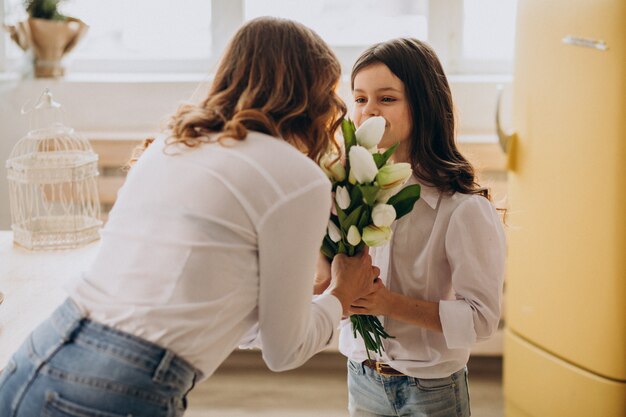 Kleines Mädchen, das Mutter mit Blumen am Muttertag begrüßt