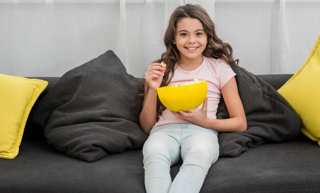 Kleines Mädchen, das Popcorn im Wohnzimmer isst