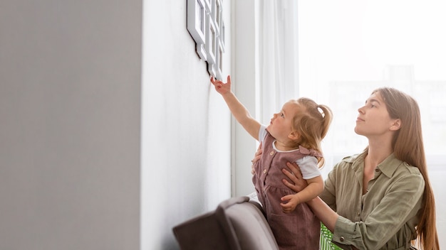 Kleines Mädchen, das Rahmen an der Wand berührt