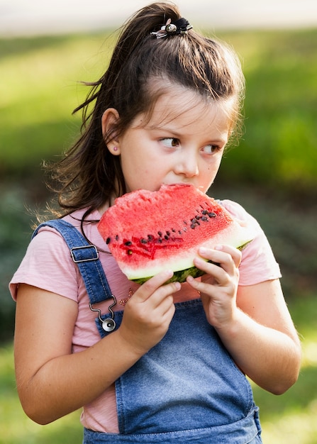 Kleines Mädchen, das Scheibe der Wassermelone genießt