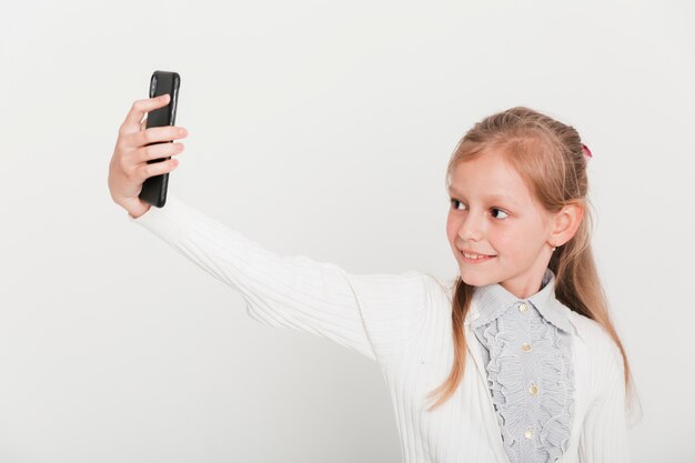 Kleines Mädchen, das selfie mit Smartphone nimmt