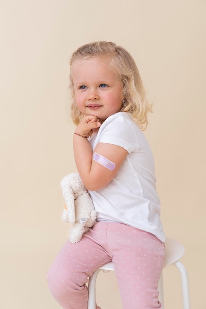 Kleines Mädchen, das Spielzeug hält, nachdem es einen Impfstoff erhalten hat