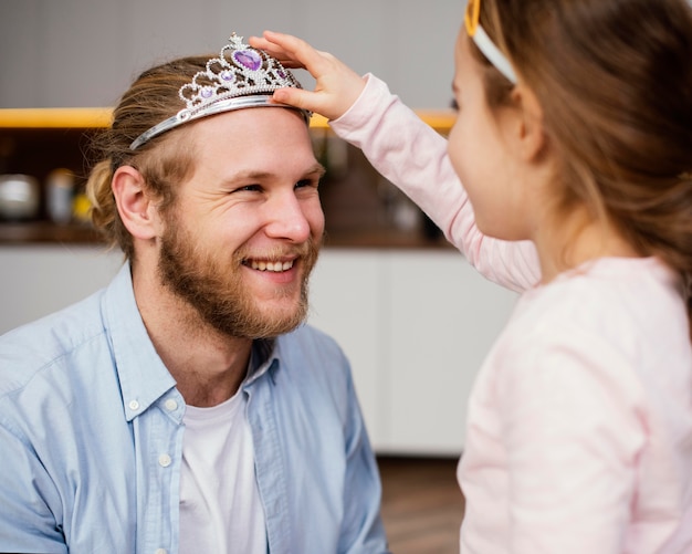 Kostenloses Foto kleines mädchen, das tiara auf vaters kopf legt