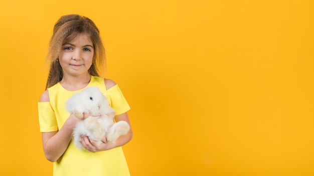 Kleines Mädchen, das weißes Kaninchen anhält