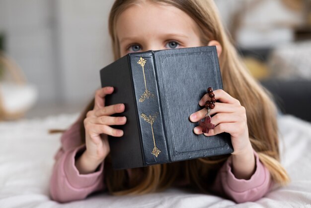 Kleines Mädchen der mittleren Aufnahme, das Bibel hält