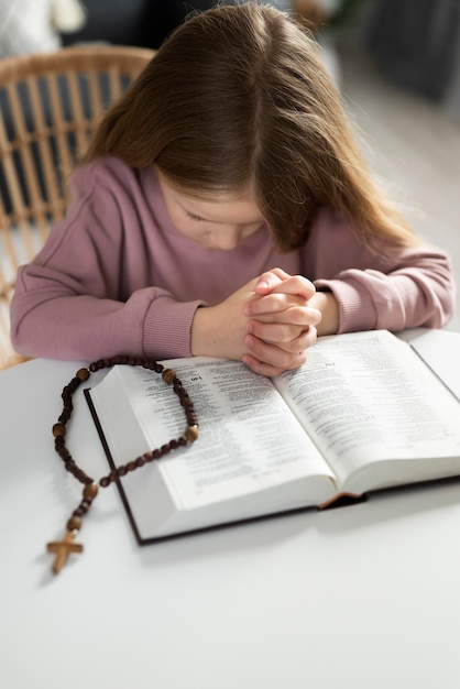 Kleines Mädchen der mittleren Aufnahme, das zu Hause betet