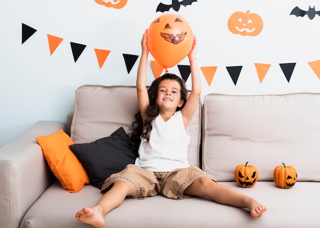 Kleines Mädchen der Vorderansicht, das einen Halloween-Ballon hält